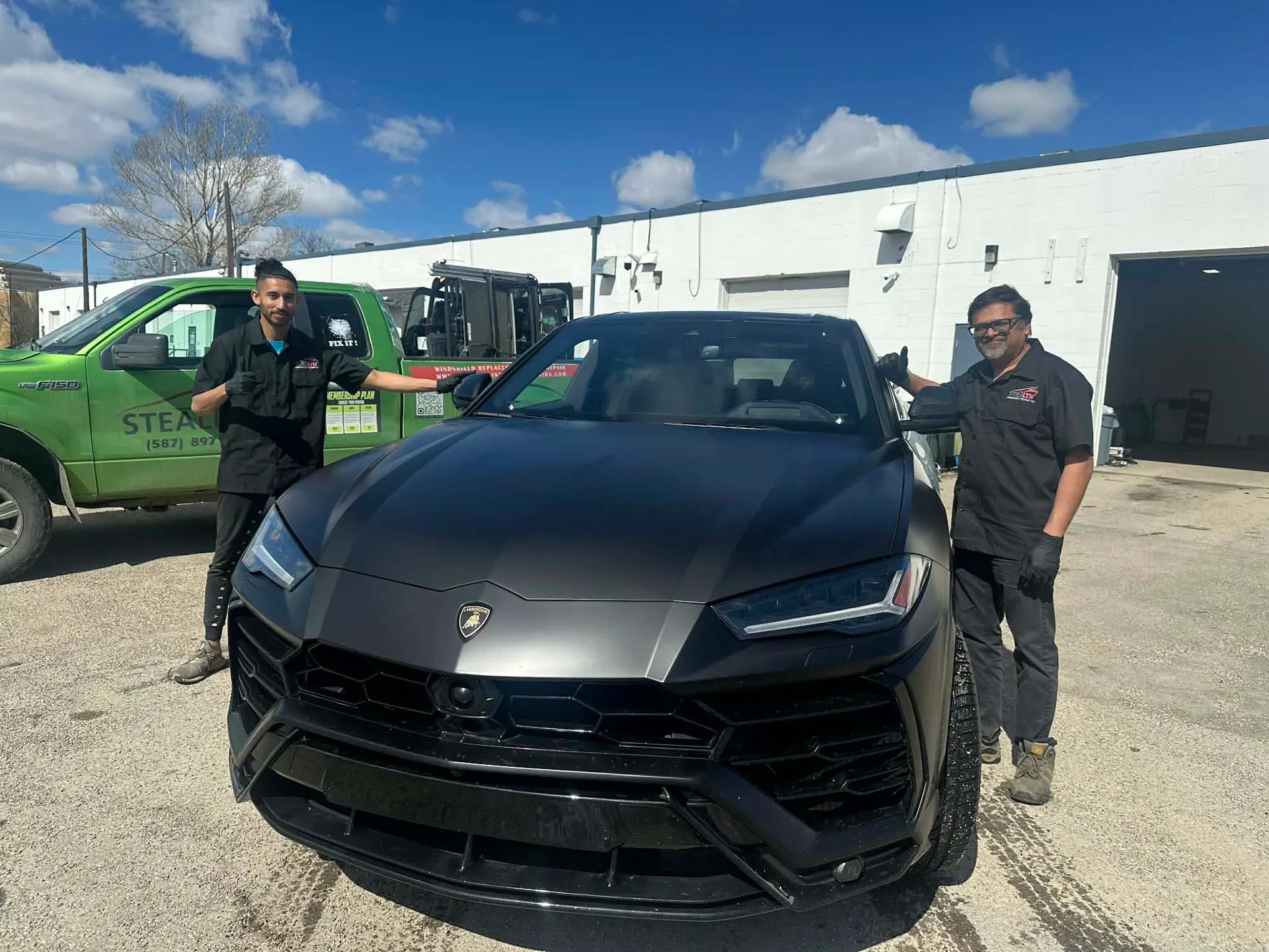 Two Stealth technicians just finished a mobile windshield chip repair on a magnificent black Lamborghini Urus